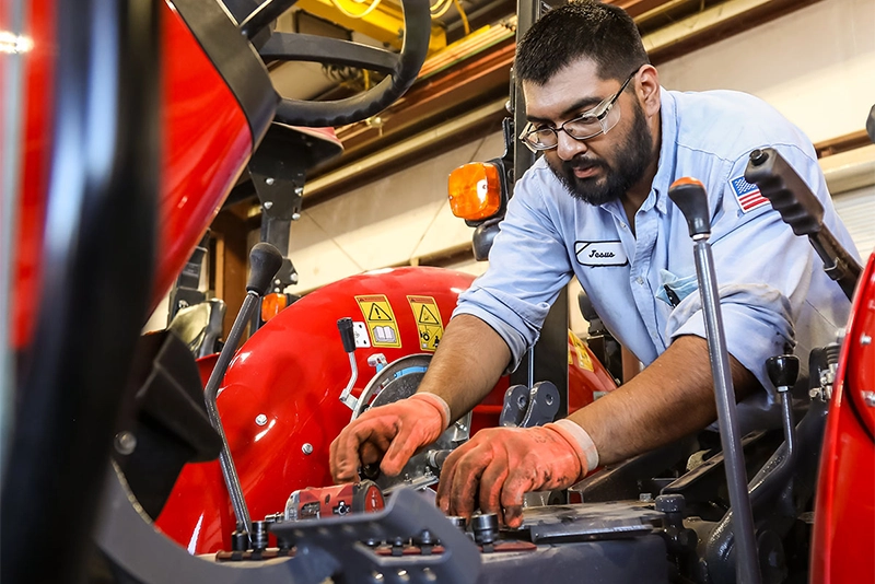 service technician performing routine maintenance on a Massey Ferguson compact tractor.